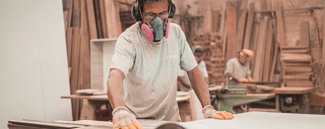 Carpenter sawing wood with a mask to prevent lung disease