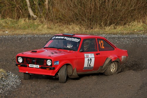 red vintage ford escort with modifications spray gravel on a tight corner t ni rally event